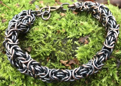 Armband av ca. 200 koppar- ringar, oxiderat, bredd 14 mm längd 19-21,5 cm. 600:-